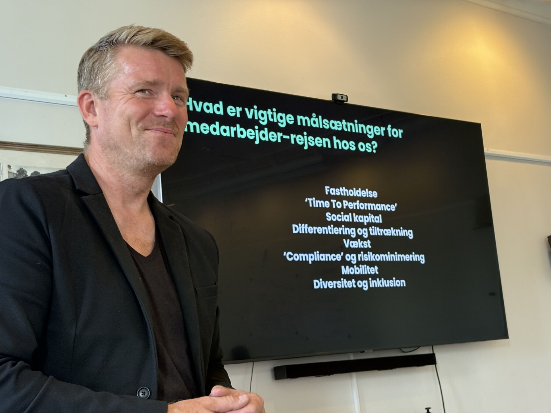 Christian Harpelund foran en slide om målsætninger for medarbejderrejsen